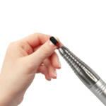 Une main avec des ongles en plein manucure et en ponçage avec un embout de ponceuse L'UGX